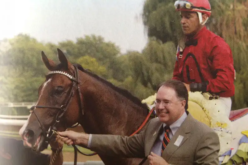 Brant Laue stands next to Gun Salute at a racetrack